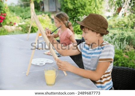 group of children  paints watercolors sitting at a table in a summer garden. art therapy.  KnowledgeForAll. Generation Z. Happy childhood. master classes in the fresh air
