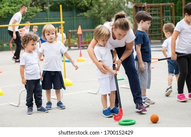 Group of children playing hockey within polygon.  Sport school. Coach helping - Powered by Shutterstock