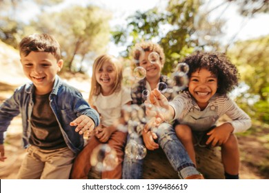 Group of children playing with soap bubbles outdoors. Friends trying to catch the bubbles. - Powered by Shutterstock