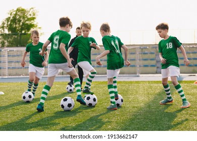 Group of children playing soccer on training session. Kids in football club wearing blue jersey shirts and soccer kits. Happy boys practicing football with coach on a sunny day - Powered by Shutterstock