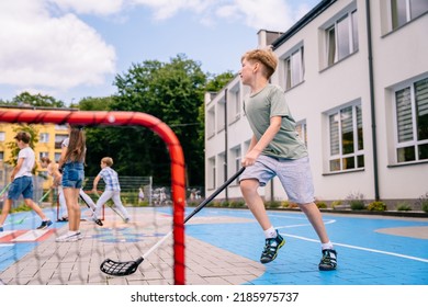 Group of children playing street hockey on a city holiday on the playground. Summer activites for children concept.