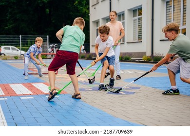 Group of children playing street hockey on a city holiday on the playground