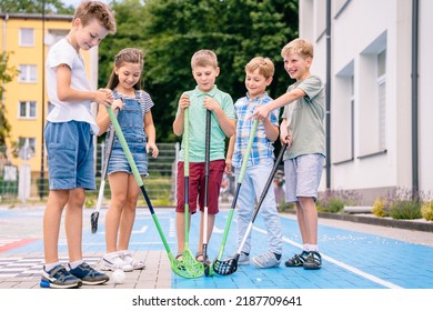 Group of children playing street hockey on a city holiday on the playground. Portrait of group of five kids hockey ball player with hockey sticks.