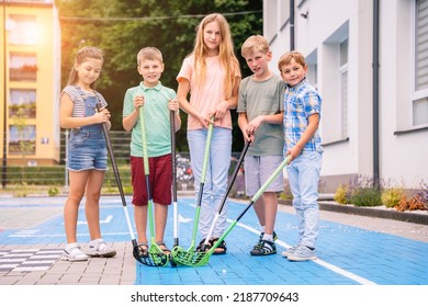 Group of children playing street hockey on a city holiday on the playground. Portrait of group of five different age kids hockey ball player with hockey stick.