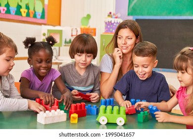 Group Of Children Plays Together In Daycare With An Educator And Building Blocks