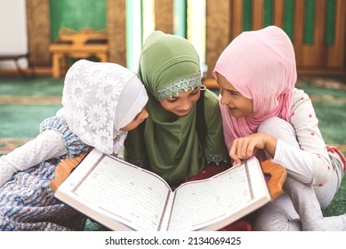 Group of a children reading a holy book Quran in the mosque. Happy Muslim family. Muslim girls in hijab studying Islam religion. 