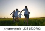 group of children run across the field on the grass. happy family kid lifestyle dream concept. children running in a field with tall grass on the sunset. girls holding hands in the foreground
