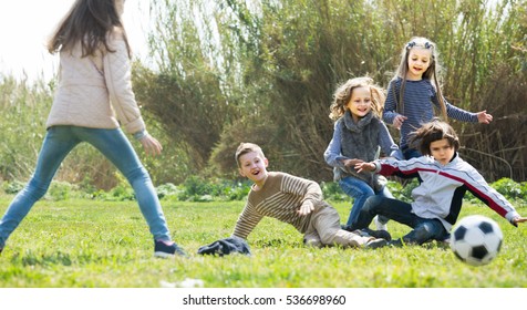 Group Of Children Running After Ball In Spring Park