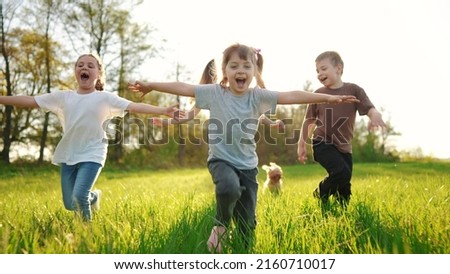 group of children running in the park. happy family baby kid dream concept. kindergarten. children hands to the sides play pilots plane run on sun the grass in the summer in the park