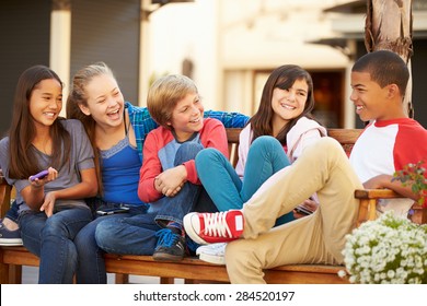 Group Of Children Sitting On Bench In Mall