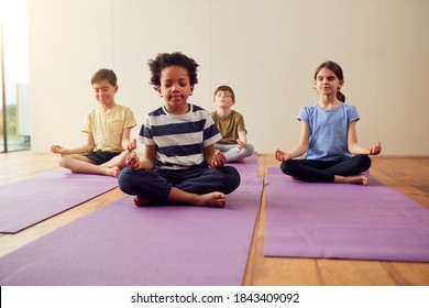 Group Of Children Sitting On Exercise Mats And Meditating In Yoga Studio - Powered by Shutterstock