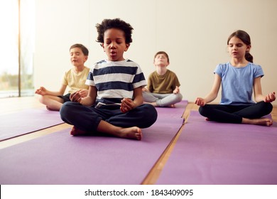 Group Of Children Sitting On Exercise Mats And Meditating In Yoga Studio - Powered by Shutterstock