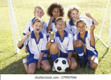 Group Of Children In Soccer Team Celebrating With Trophy