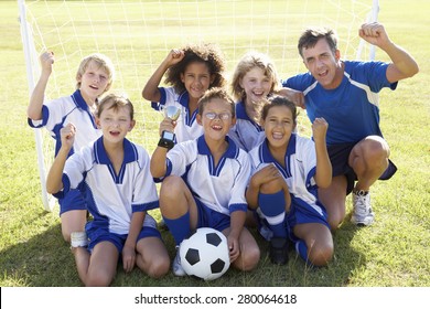 Group Of Children In Soccer Team Celebrating With Trophy