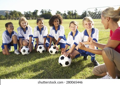 Group Of Children In Soccer Team Having Training With Female Coach