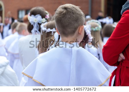 A group of children in solemn white clothes is waiting in front of the entrance to the church. Preparation for the first Holy Communion and for the Holy Mass.