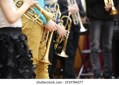 A Group Of Children Students Young Musicians Boys And Girls With Musical Instruments Trumpet Standing In A Row In The Classroom Listening Attentively.The Concept Of School Music Education