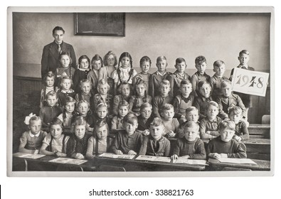 Group of children and teacher in the classroom. Retro picture of classmates in the school. Vintage photo with original film grain, blur and scratches from ca 1948