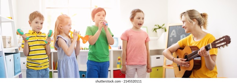 Group Of Children And Teacher In The Music Class. Kids Playing On The Musicial Instruments. Singer Solo Performance.