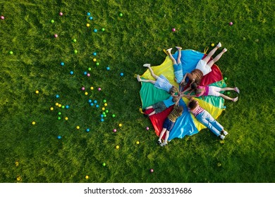 Group of children with teachers holding hands together on rainbow playground parachute in park, top view. Summer camp activity - Powered by Shutterstock