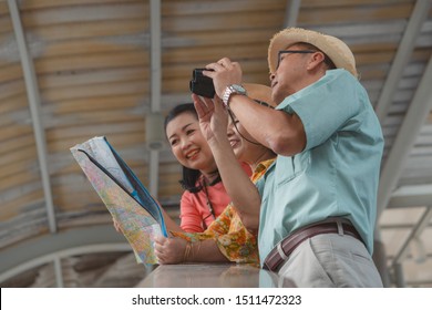 Group Of Chinese Asian Friends Tourists With Map On Hands Having Sightseeing City Tour In Bangkok