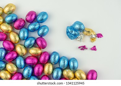Group of chocolate easter eggs in blue, yellow and pink paper. They are isolated on a white background