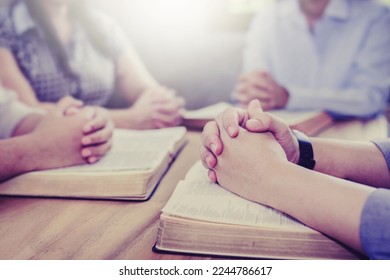 A group of christian people hands praying on bible together around wooden table with window light,  bible study group with opy space for text, prayers meeting in church, church member fellowship - Shutterstock ID 2244786617