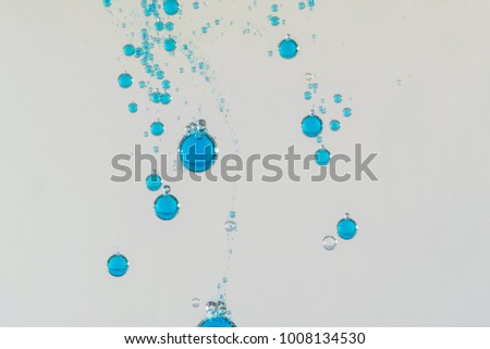 A group of clear bue water bubbles falling over a light background