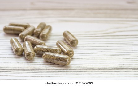 Group of clear CBD Cannabidiol capsules on bright wooden backdrop