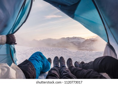 Group of climber are inside a tent with open for view of blizzard on snow mountain