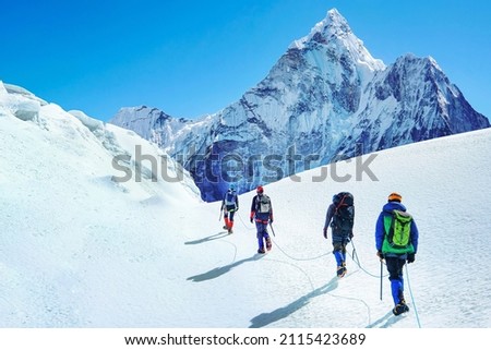 Group of climbers reaches the summit of mountain peak enjoying the landscape view.