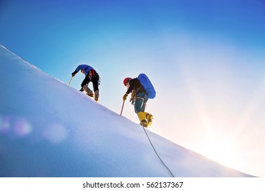 Group of climbers reaches the top of mountain peak. Climbing and mountaineering sport. Teamwork concept.