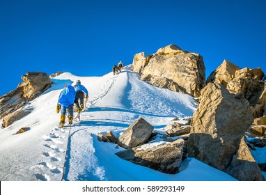 Group Of Climbers Reaches The Top Of Mountain Peak. Climbing And Mountaineering Sport. Teamwork Concept.