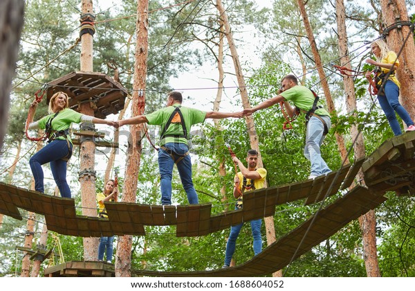 Group climbing in the high ropes course as a team\
building activity in\
summer