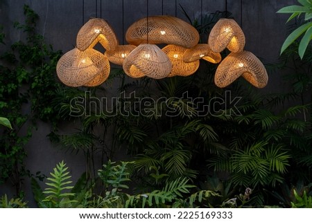 Group cluster of rattan lampshades in the tropical garden in evening lights on 