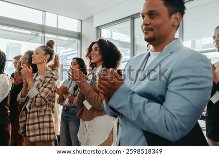 Group of colleagues clapping and appreciating a presentation in a modern office setting, showcasing teamwork and collaboration.