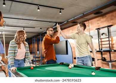 A group of colleagues from a coworking space gather around a pool table, enjoying a break and building team camaraderie. - Powered by Shutterstock