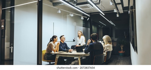 Group of colleagues having a meeting in a transparent boardroom. Team of diverse business professionals having a discussion during a briefing. Businesspeople collaborating on a new project. - Shutterstock ID 2072837654