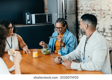 Group of colleagues sharing a joyful lunch in an office. Smiling people engage in conversation over a casual meal, creating a lively team bonding atmosphere. - Powered by Shutterstock