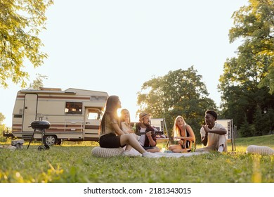 A group of college friends spend time together traveling in a camper van. A bearded middle-aged boy plays guitar. - Powered by Shutterstock