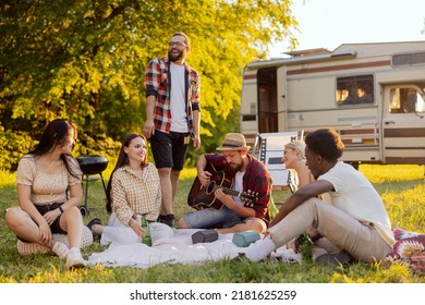 A group of college friends spend time together singing surrounded by nature. A bearded middle-aged boy plays the guitar. The good friends travel together in their beloved old camper van. - Powered by Shutterstock