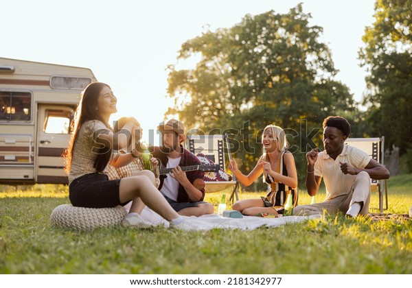 A group of college friends spend time together\
singing surrounded by nature. A bearded middle-aged boy plays the\
guitar. The good friends travel together in their beloved old\
camper van.
