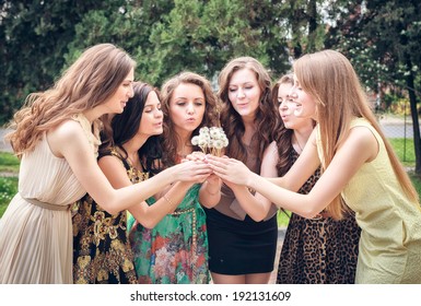 Group Of College Girls Blowing Dandelion Seeds