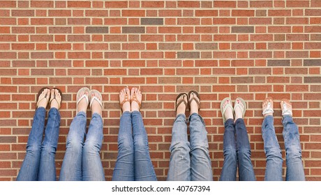 Group Of College Girls At School With Legs Up On Wall