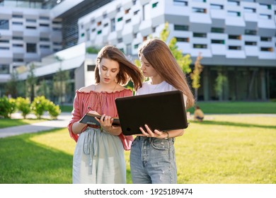 A Group Of College Girls Are Standing Near The University, Looking At A Computer, Making Notes In A Notebook.