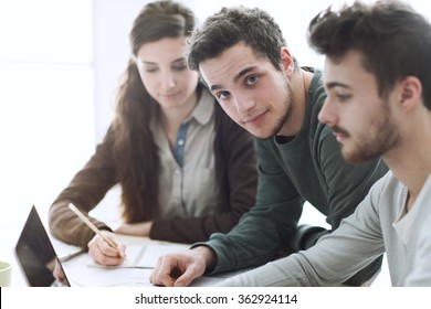 Group of college students at desk using a laptop, networking and studying together, education and learning concept - Shutterstock ID 362924114