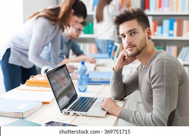 Group Of College Students Doing Homework And Studying Together, They Are Using Laptops, High Tech Classrooms And Innovation Concept