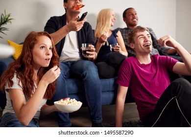 Group Of College Students In Shared House Watching TV And Eating Popcorn