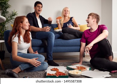 Group Of College Students In Shared House Having Night In Eating Pizza Together