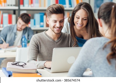 Group of college students studying in the school library, a girl and a boy are using a laptop and connecting to internet - Powered by Shutterstock